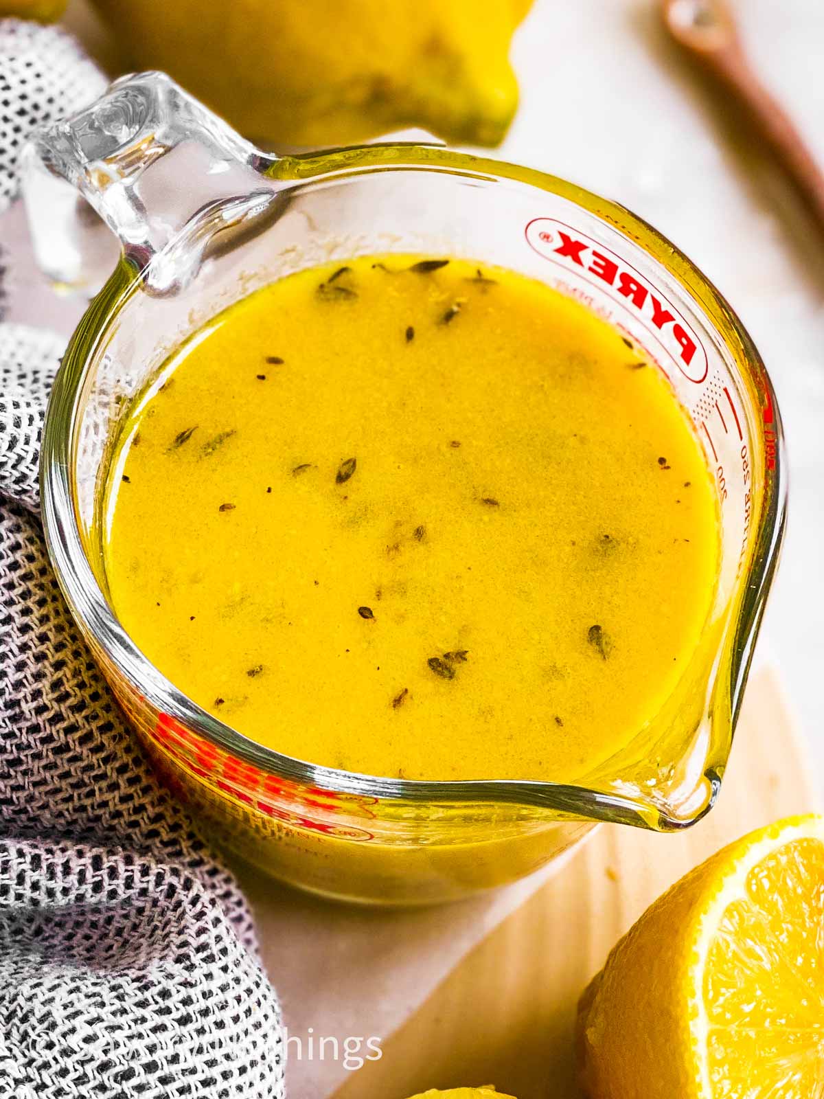 angled overhead view of lemon vinaigrette in glass measuring jug