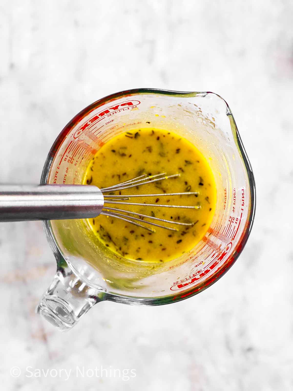 overhead view of loom vinaigrette in glass measuring jug with metal whisk