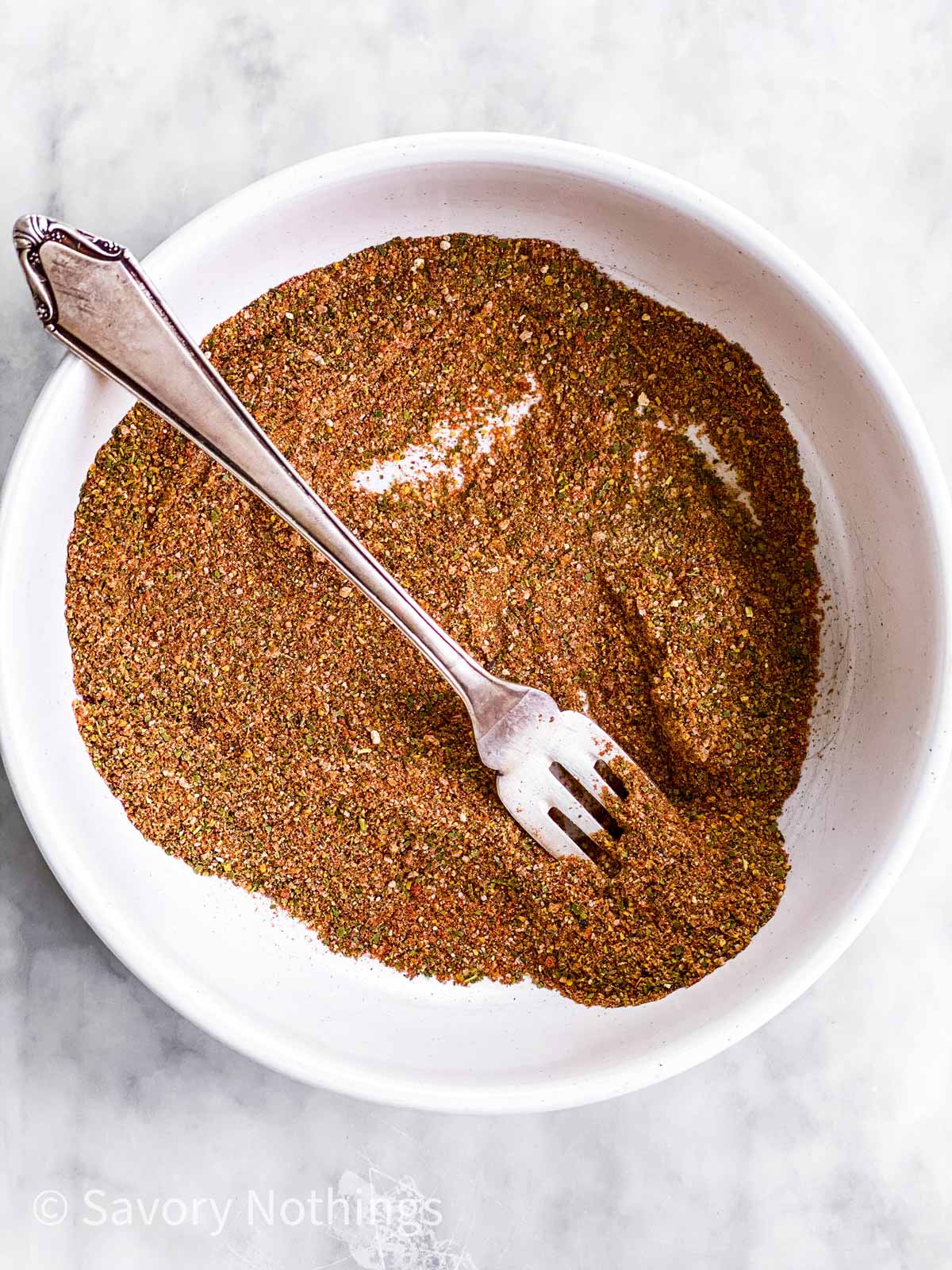 homemade old bay seasoning mix in small white bowl with a fork