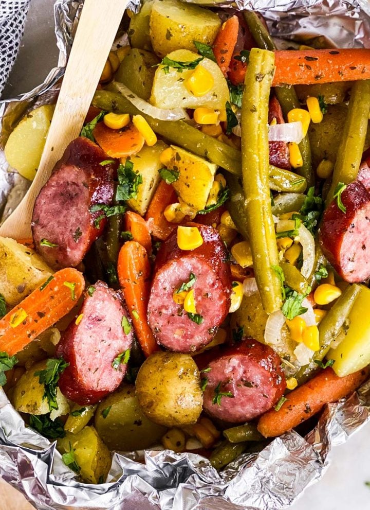 overhead close up view of opened sausage foil packet with bamboo fork stuck in