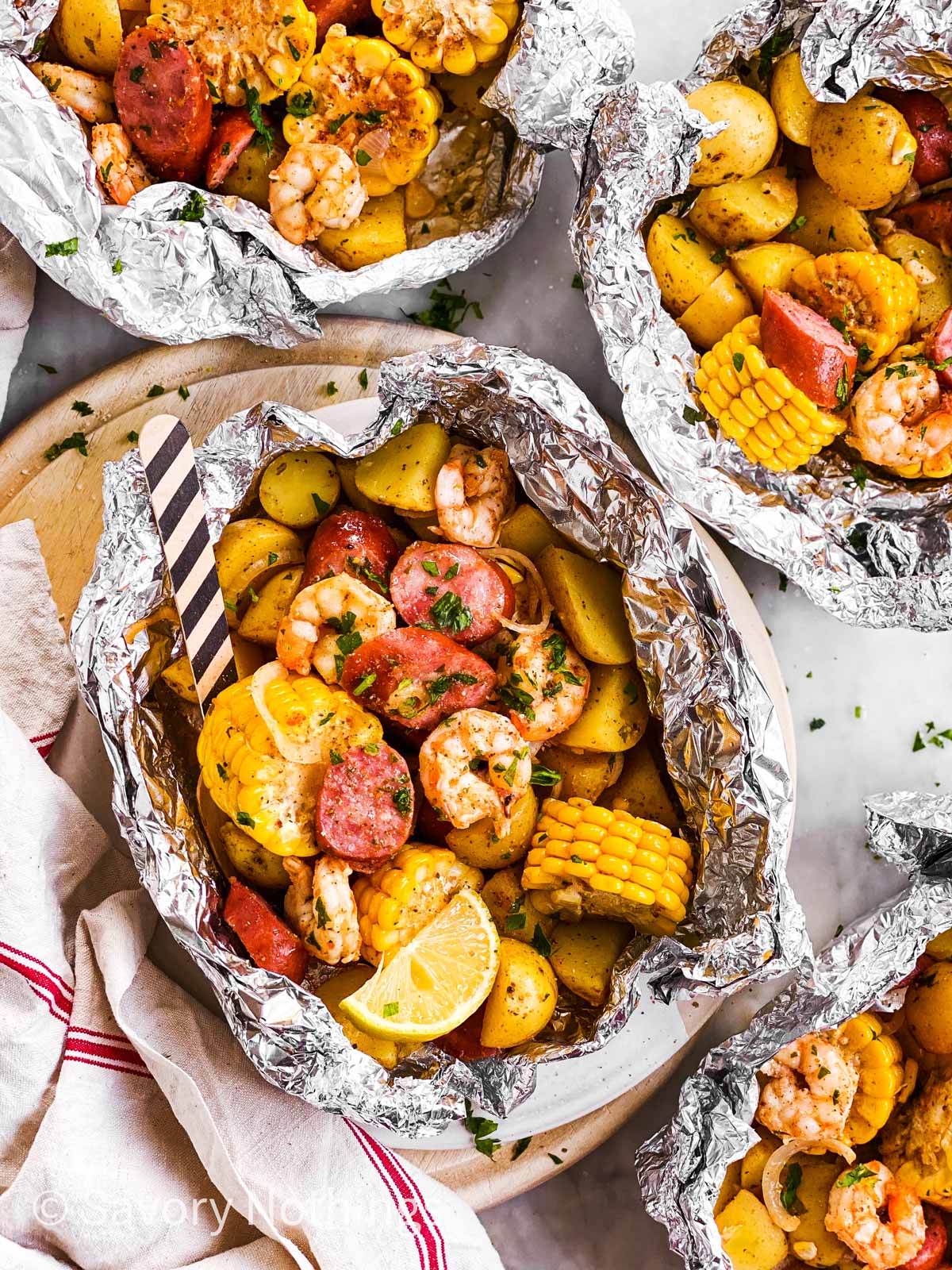 overhead view of three shrimp boil foil packets on marble surface