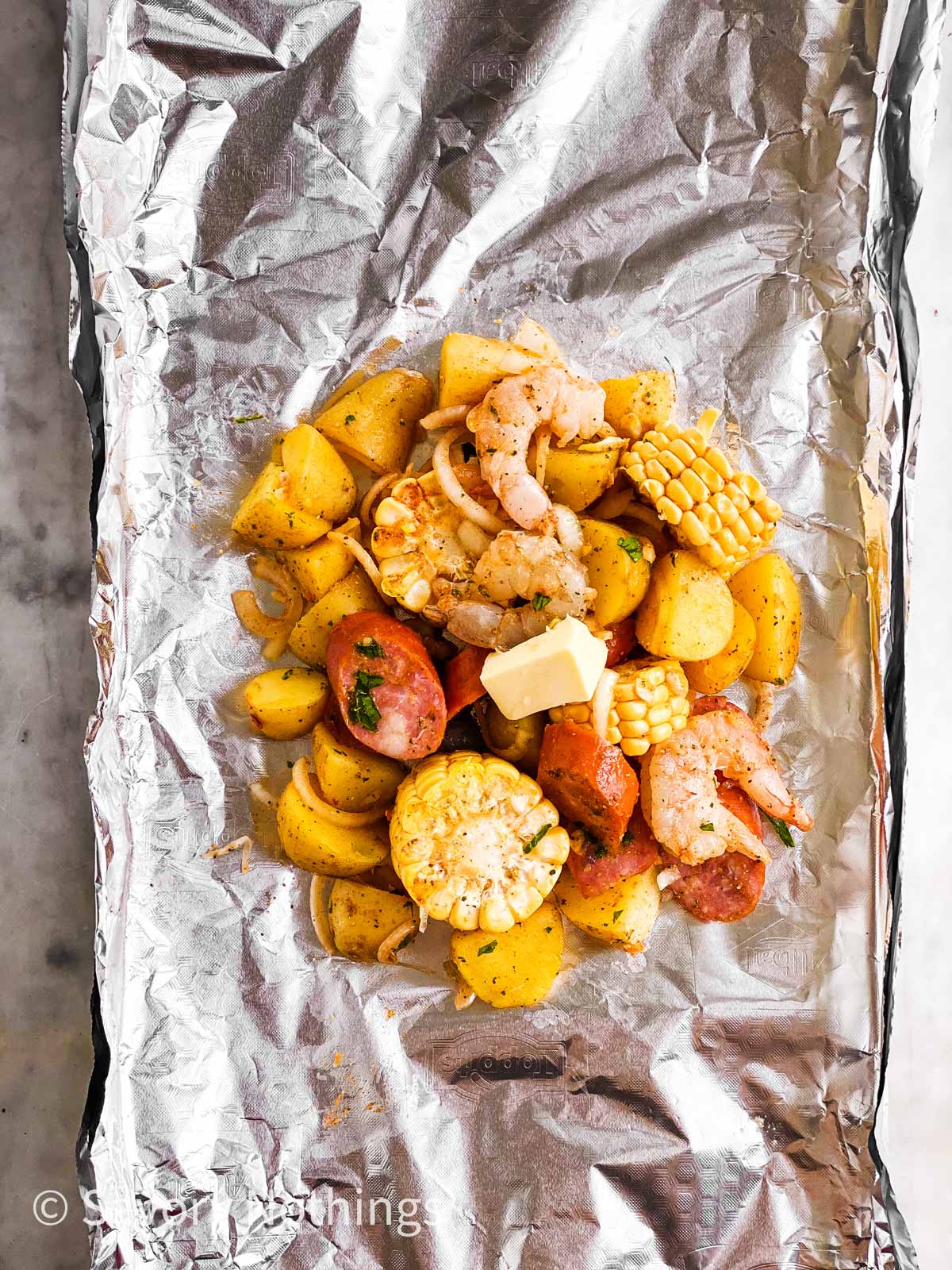 uncooked shrimp boil in middle of piece of aluminium foil