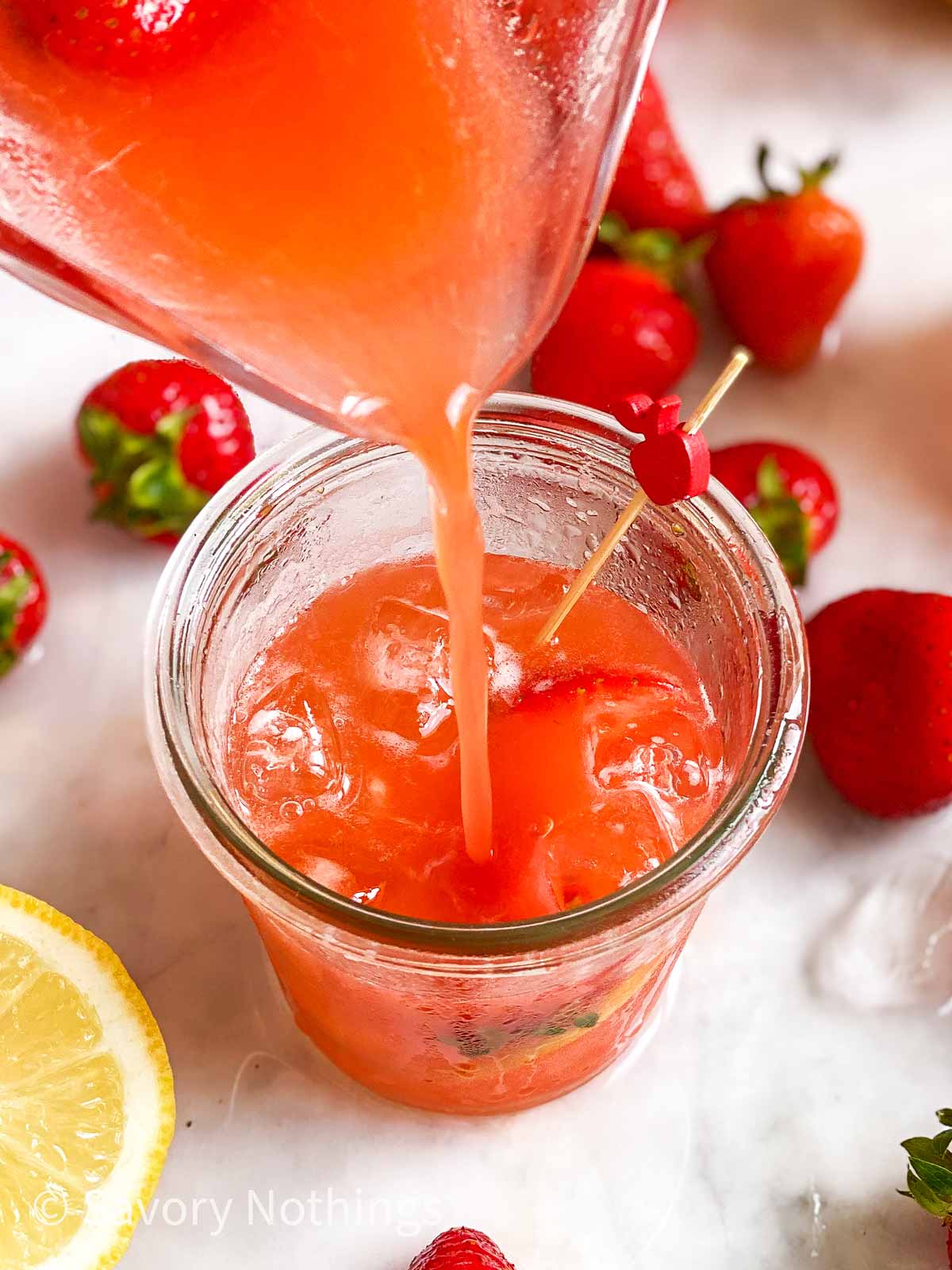 strawberry lemonade pouring from jug into glass