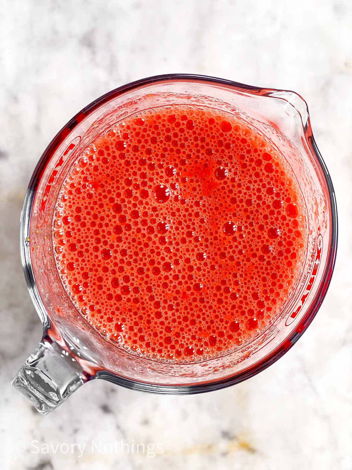 blended strawberries in glass measuring jug