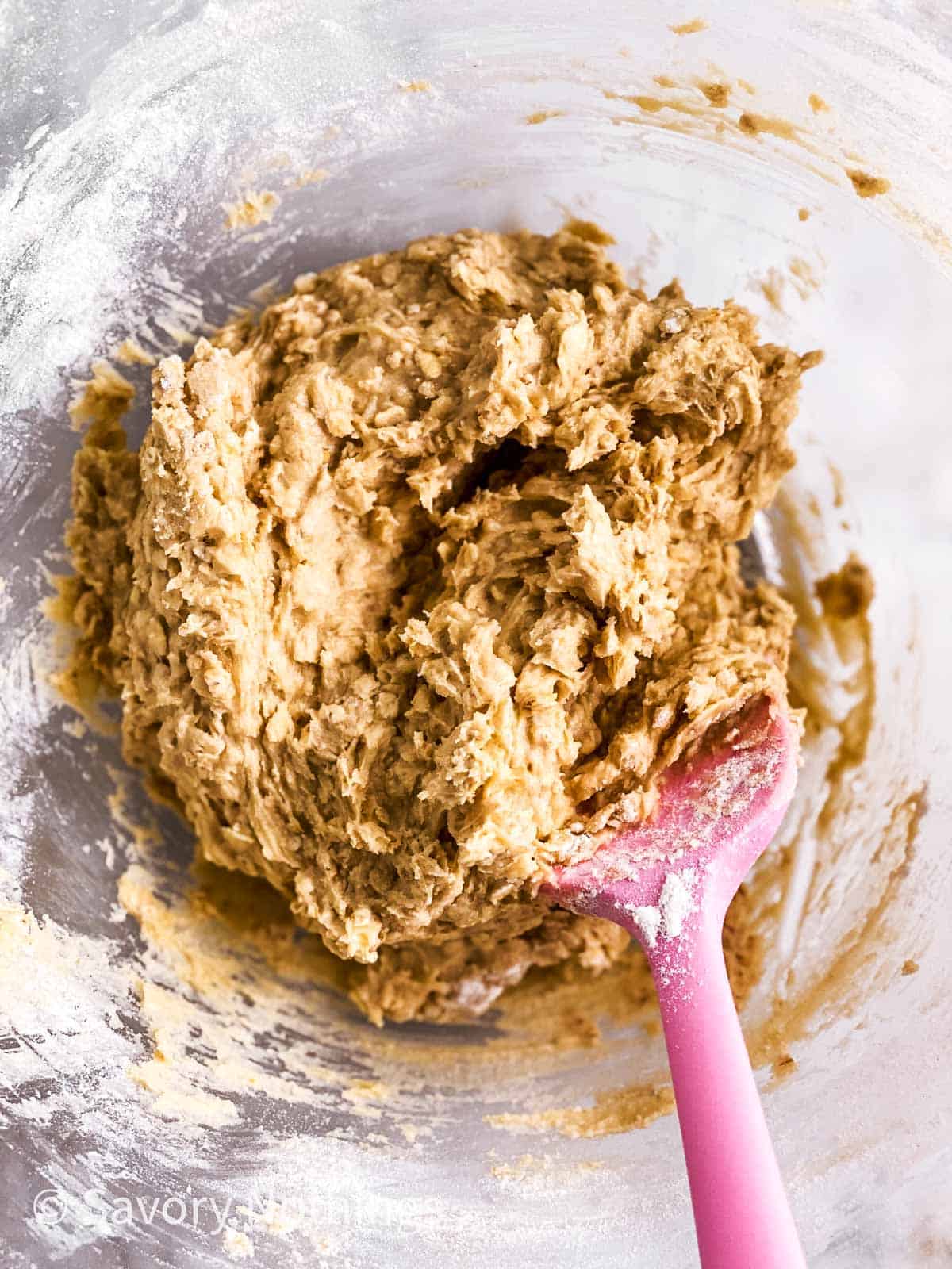 oatmeal cookie dough in glass bowl with pink rubber spatula