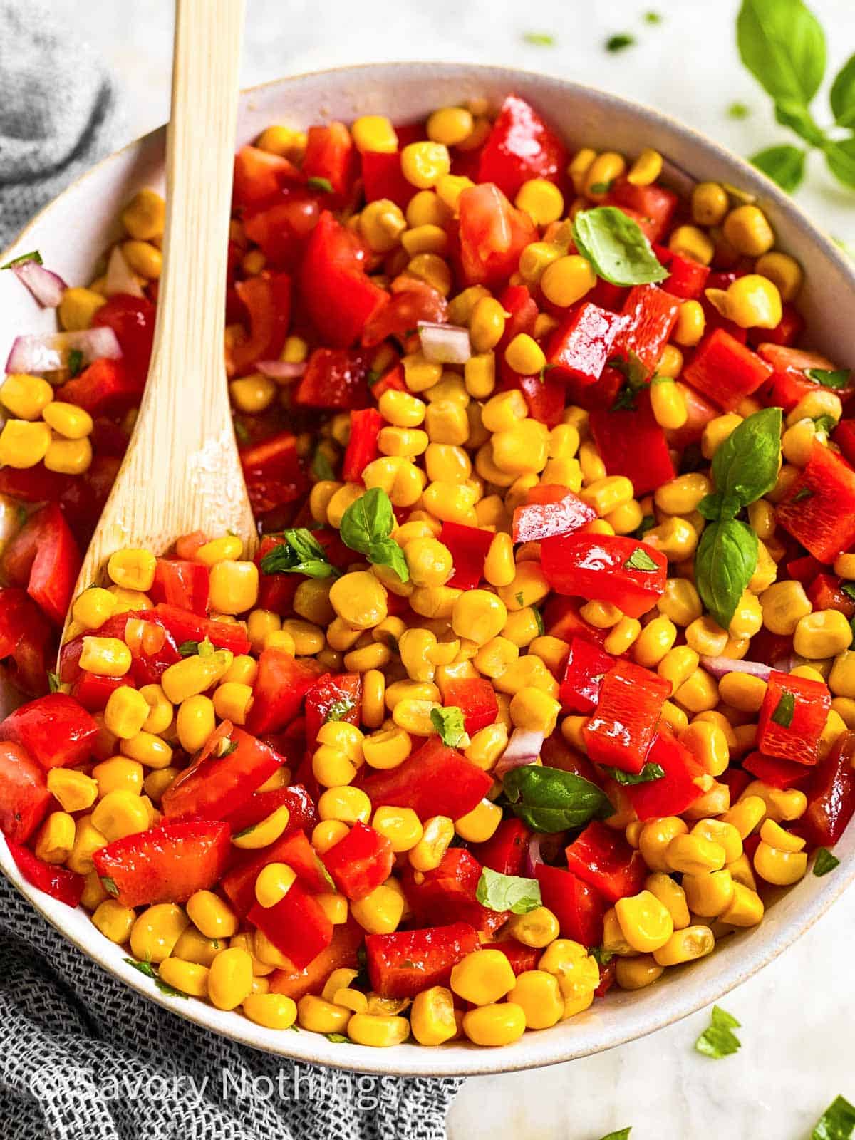 close up photo of wooden spoon in bowl with corn salad