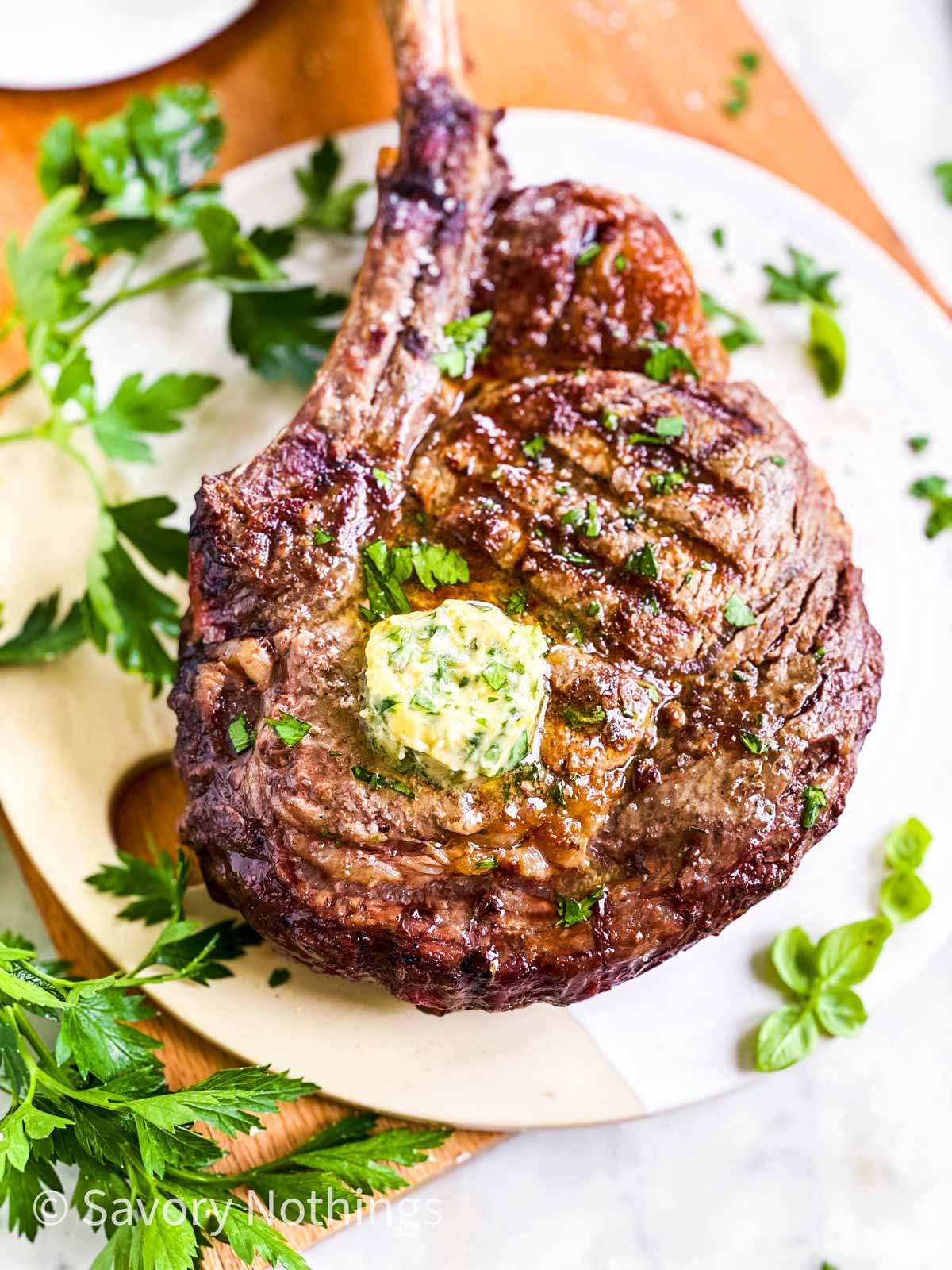 frontal view of garlic herb butter slice melting on top of grilled steak