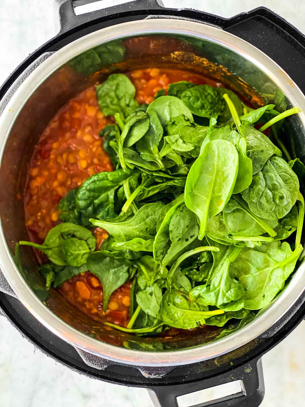 Fresh spinach on top of lentil soup in instant pot