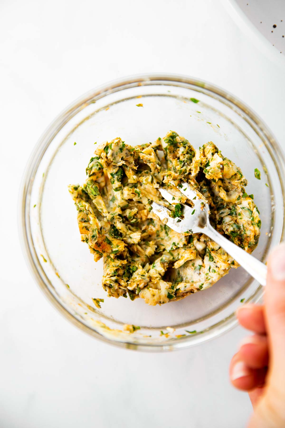 female hand using fork to mash garlic herb butter