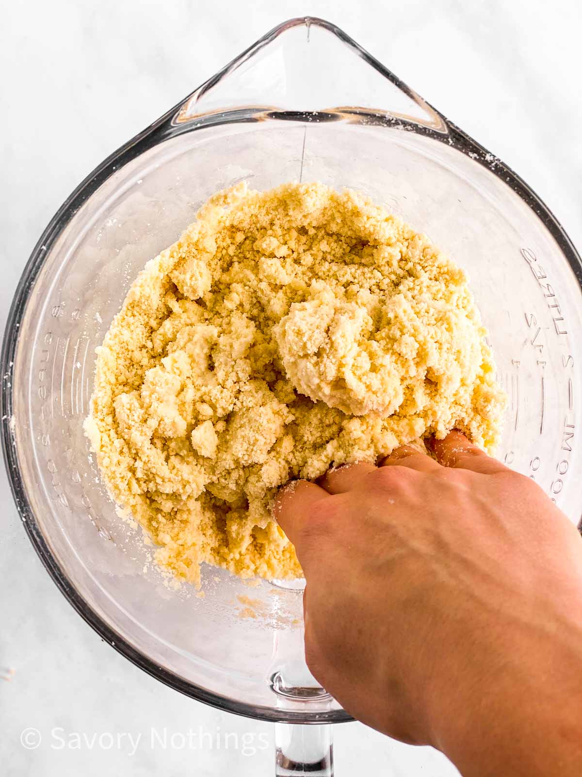 female hand stirring mixture for pie crust in glass bowl