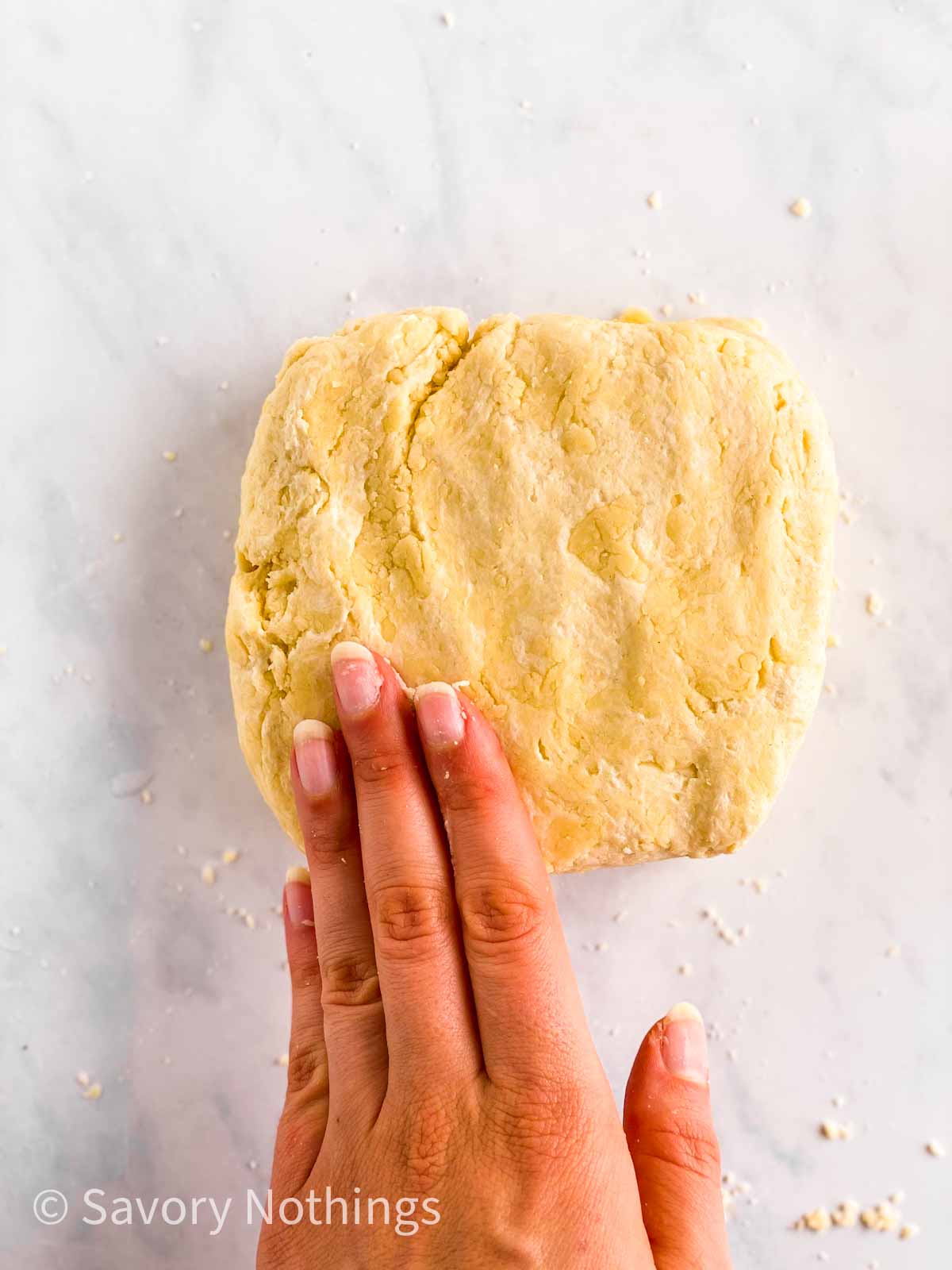 female hand pushing pie crust into ball