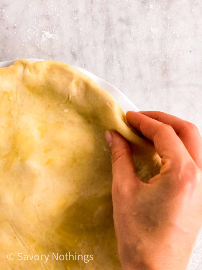 female hand sealing edges of pie crust