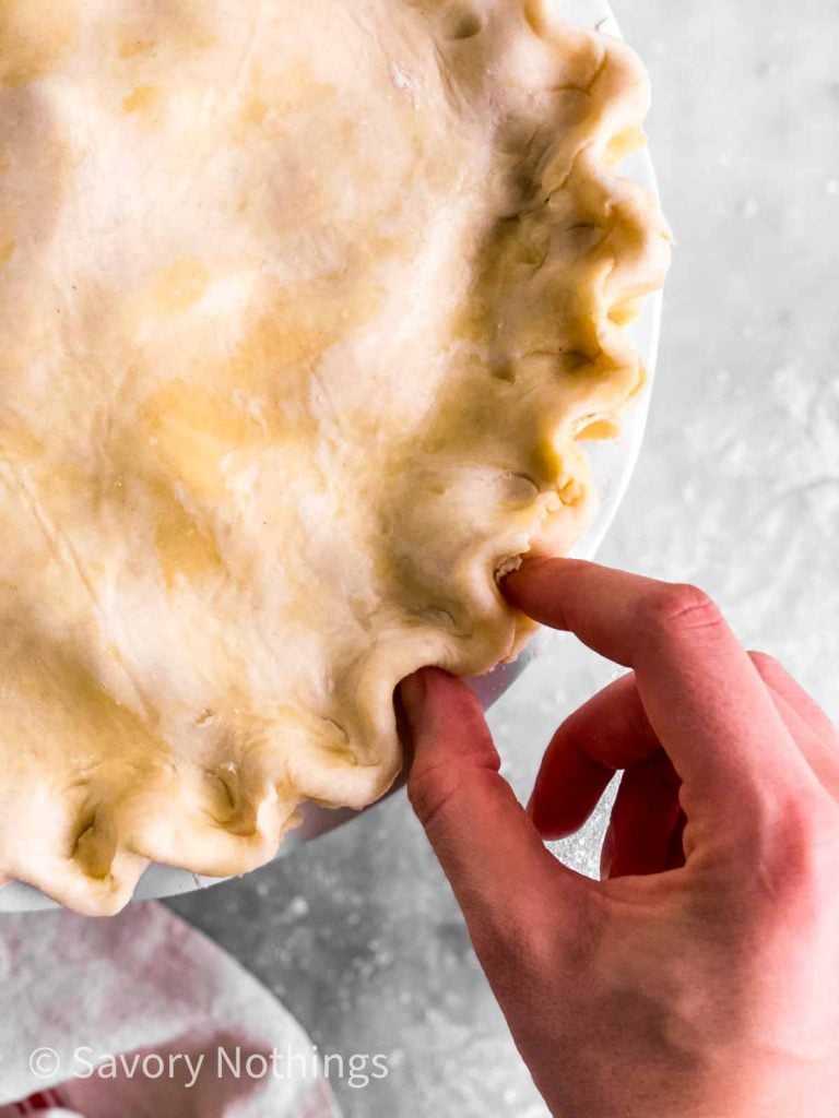 female hand fluting edge of pie crust