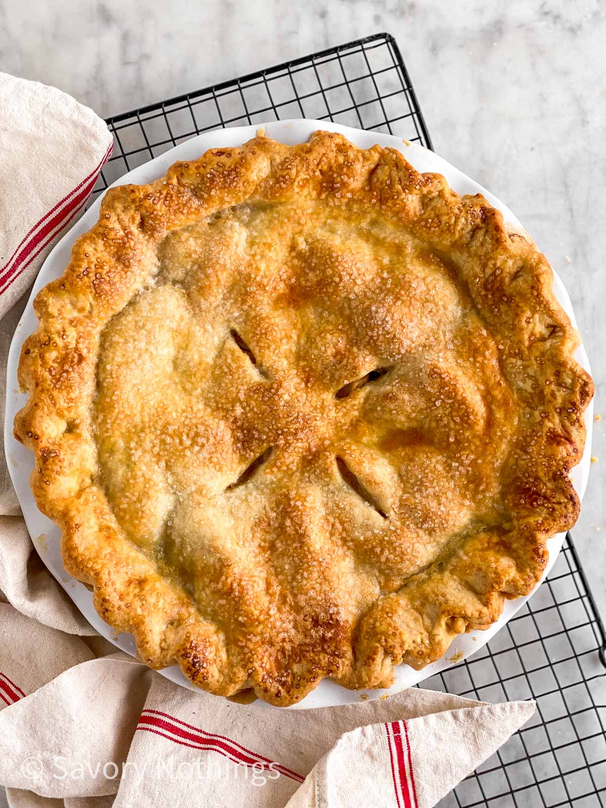 baked apple pie on black cooling rack