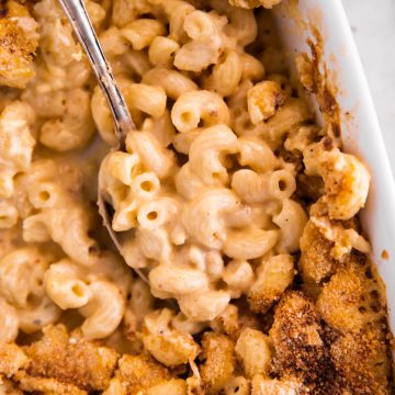 close up photo of spoon stuck in dish with mac and cheese