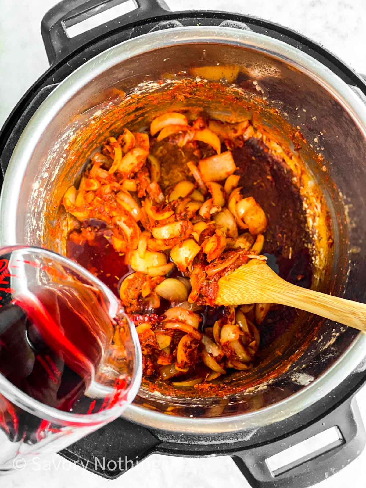 pouring red wine from glass measuring jug into instant pot