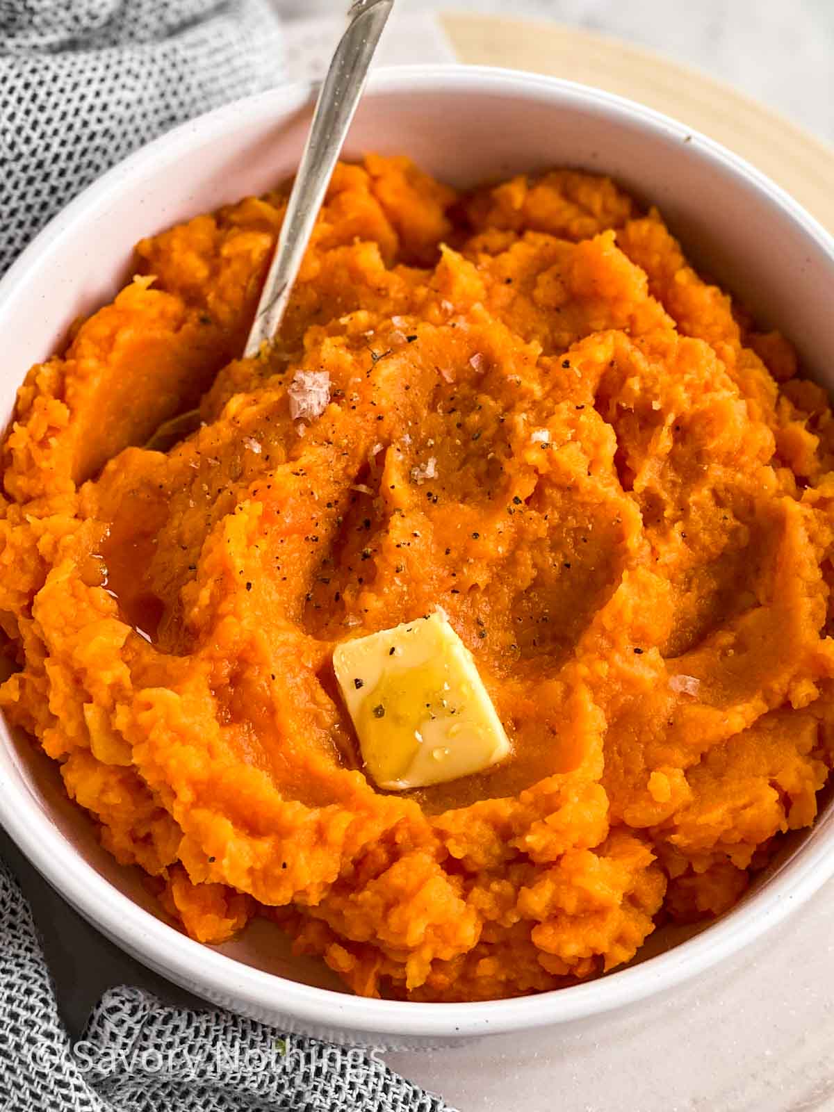 frontal view of bowl filled with mashed sweet potatoes garnished with pat of butter
