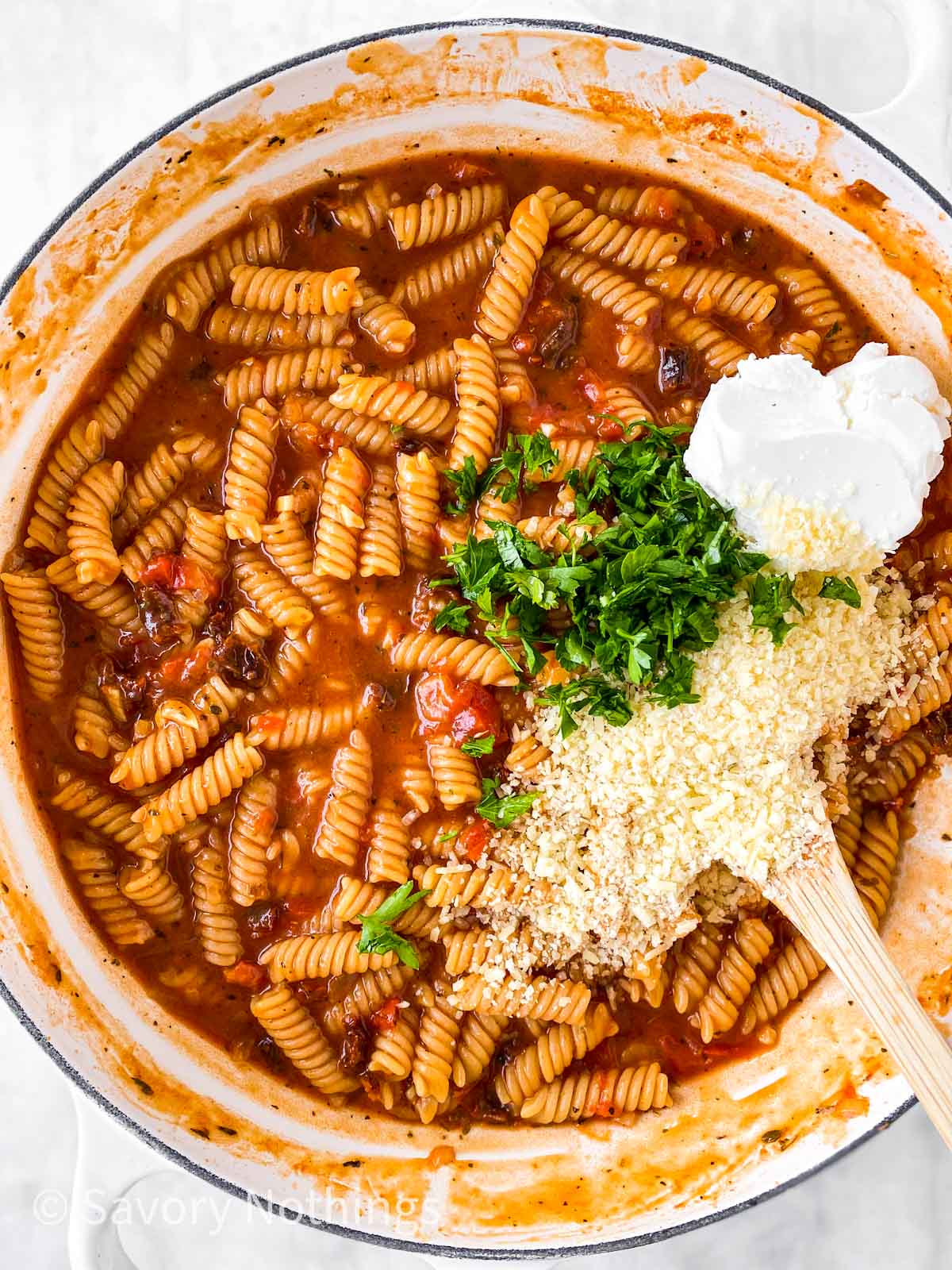 grated parmesan cheese, cream cheese and chopped parsley on top of cooked tomato pasta