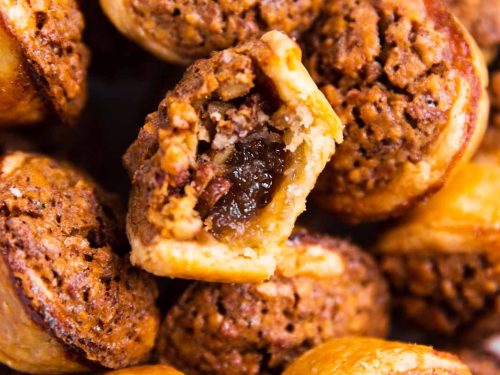 overhead view of a pile of pecan tassies, with the center one having a bite taken out