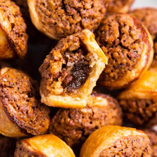 overhead view of a pile of pecan tassies, with the center one having a bite taken out