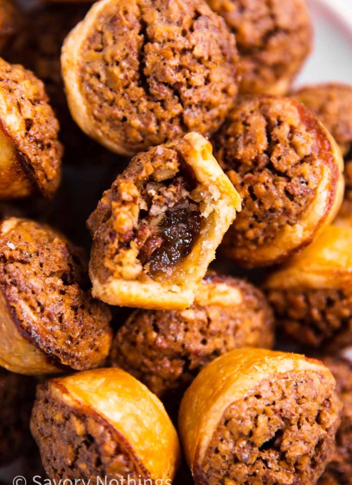 overhead view of a pile of pecan tassies, with the center one having a bite taken out