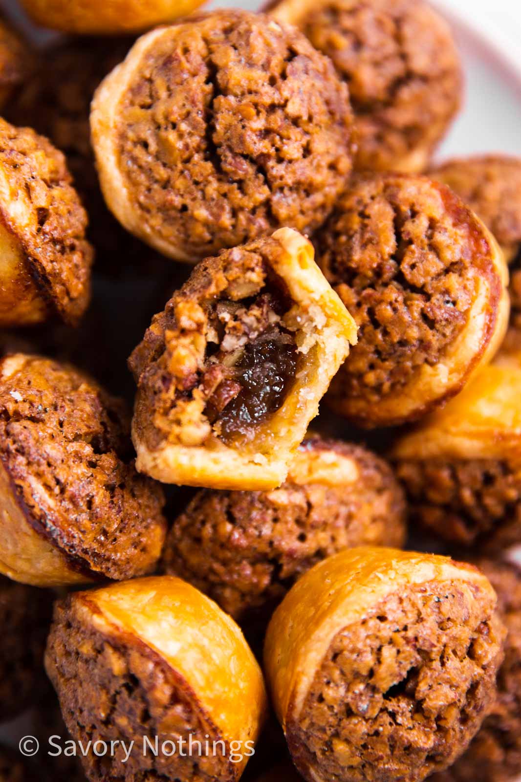 overhead view of a pile of pecan tassies, with the center one having a bite taken out