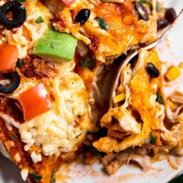 overhead view of fork stuck in plate filled with turkey enchiladas
