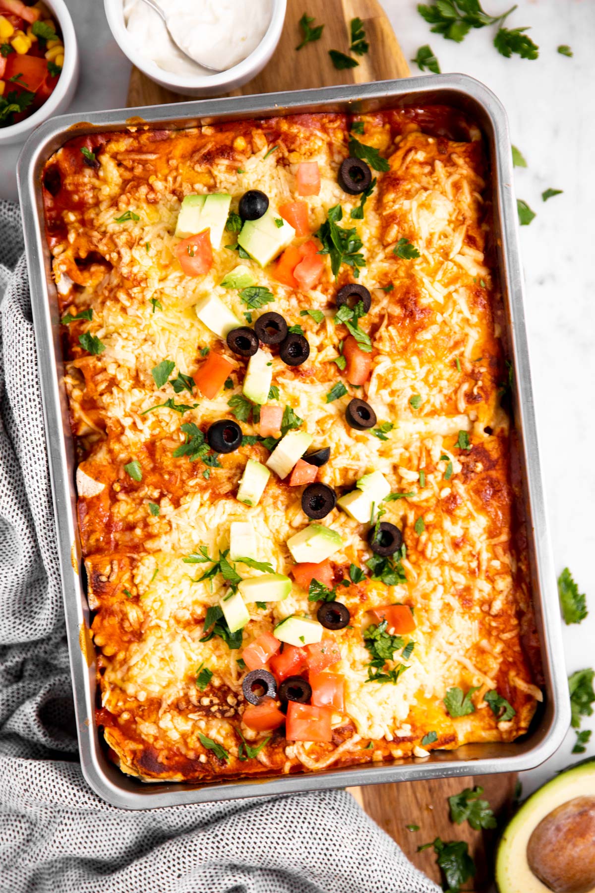 baked turkey enchiladas in casserole dish placed on wooden board