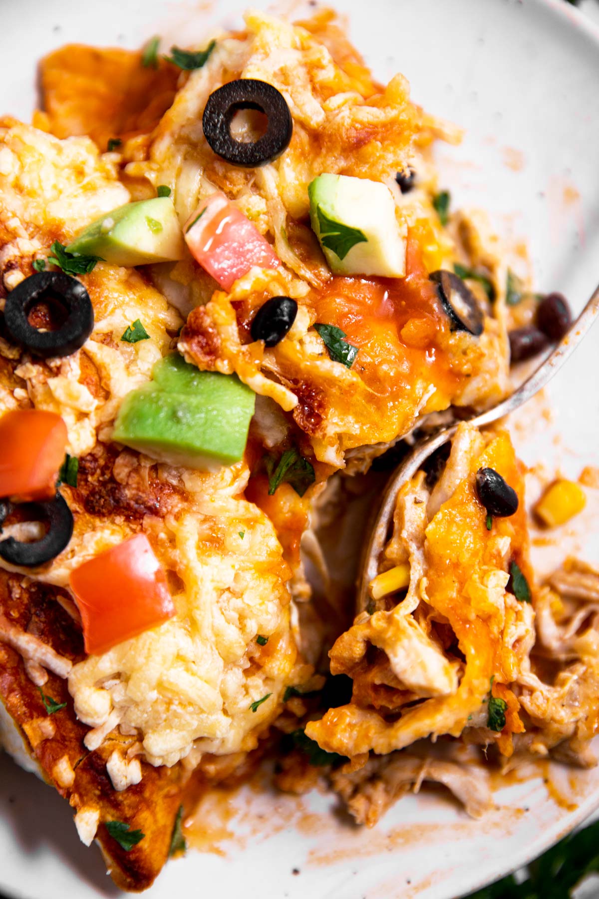 overhead view of fork stuck in plate filled with turkey enchiladas