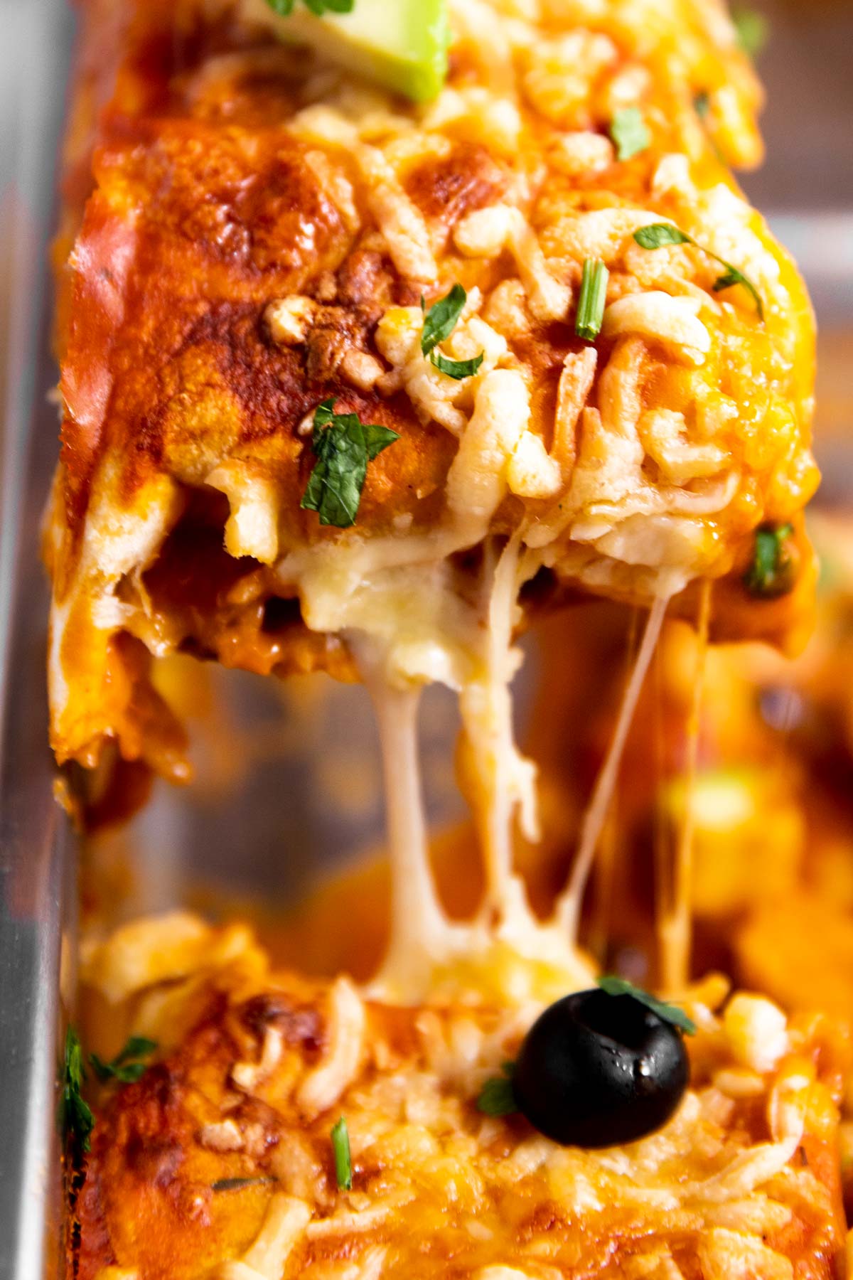 close up photo of turkey enchiladas being scooped out of casserole dish