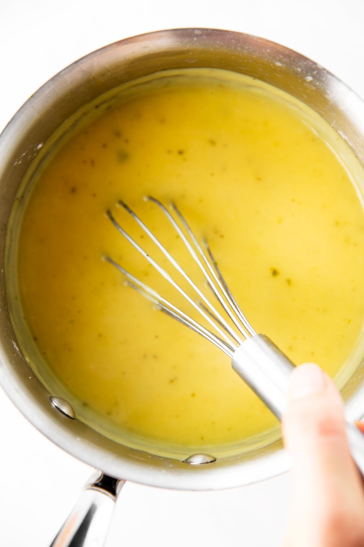 female hand whisking turkey gravy in saucepan