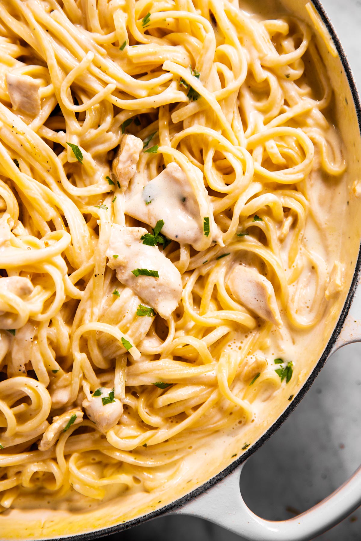 close up photo of chicken fettuccine alfredo in white enamel skillet