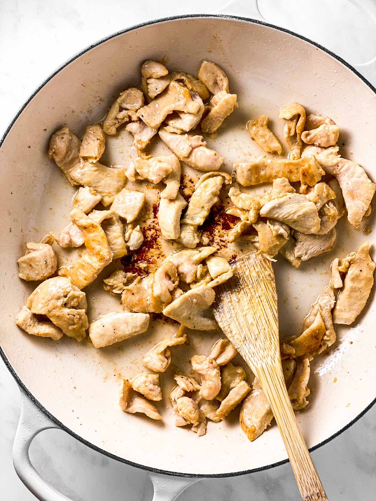 browned chicken in white enamel skillet