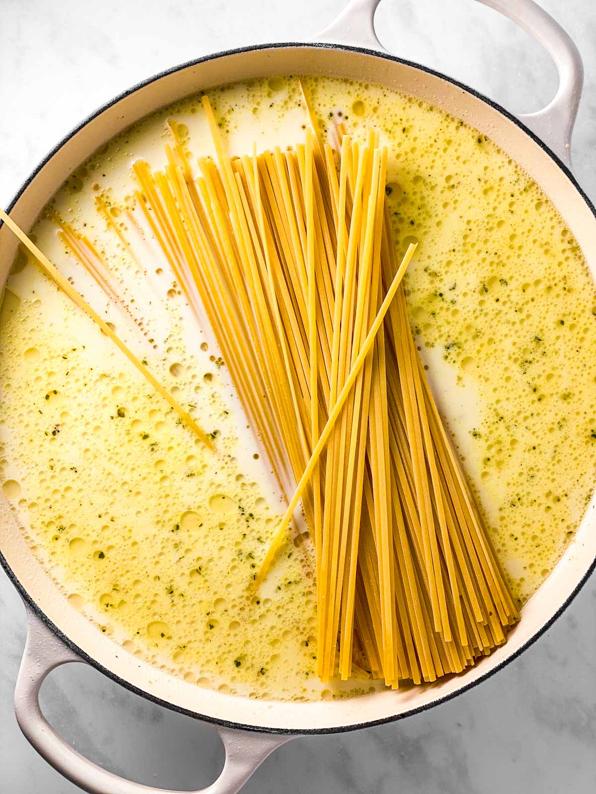 dry fettuccine in white enamel pan with milk