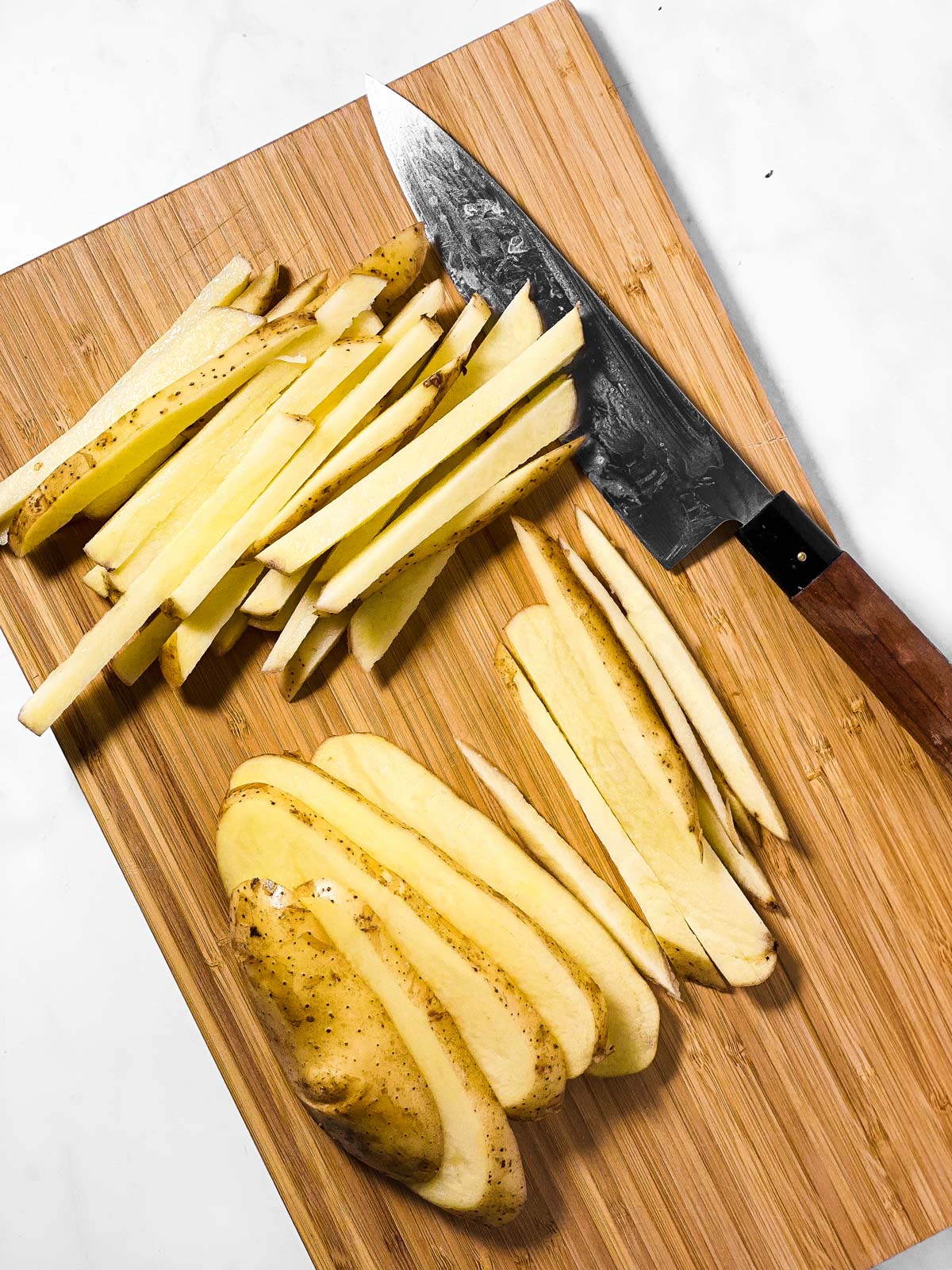potatoes cut into fries on wooden board