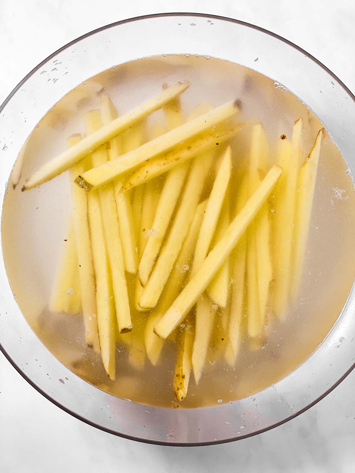 uncooked french fries in glass bowl filled with water