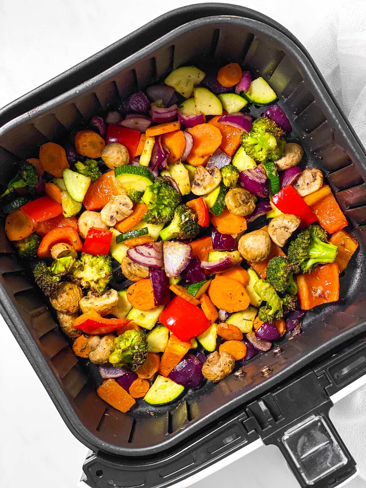 overhead view of air fryer basket filled with roasted vegetables