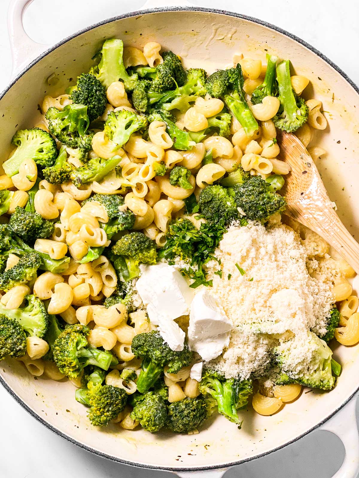 parmesan cheese and cream cheese in skillet with cooked broccoli and pasta