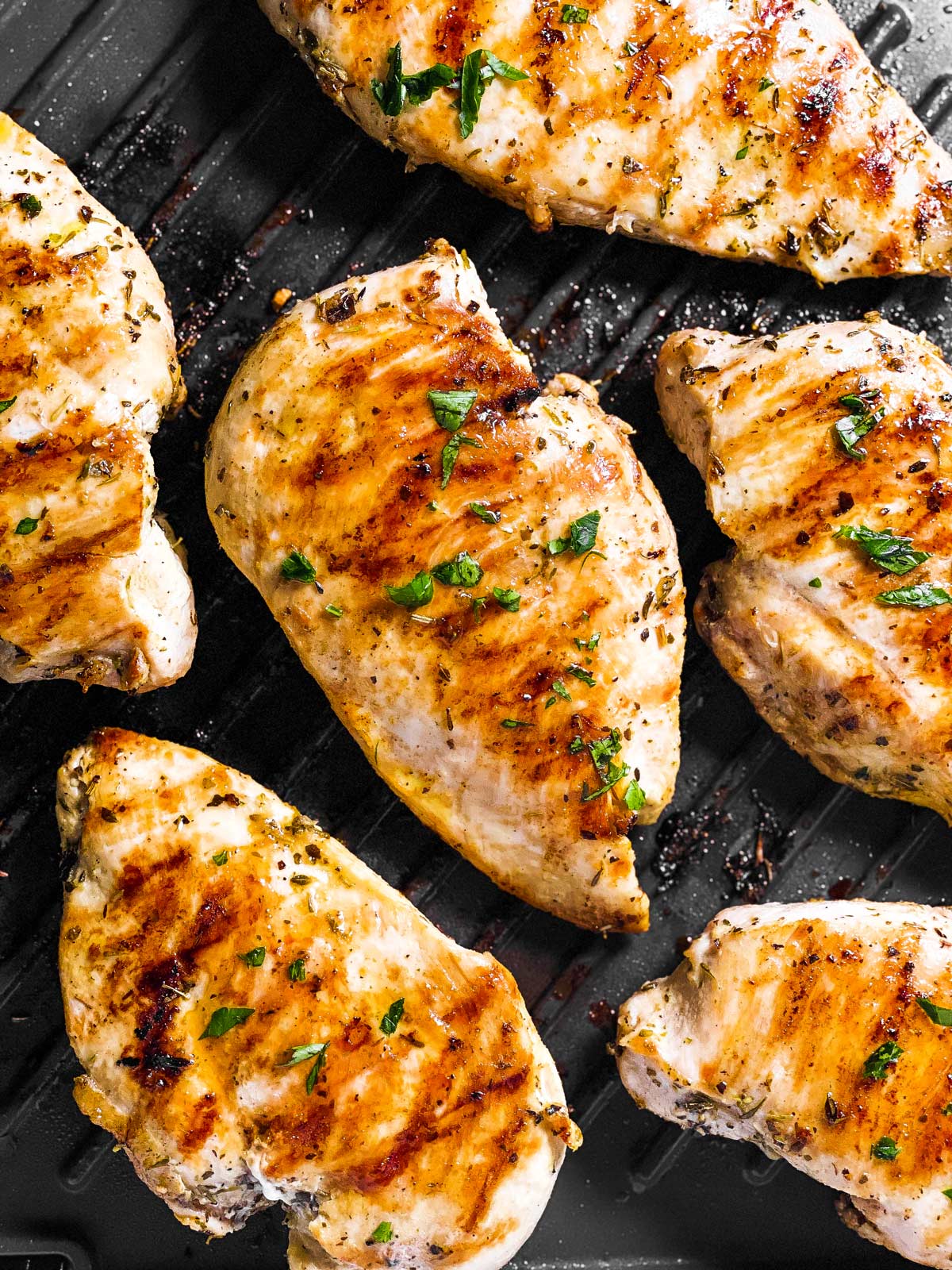 overhead view of several chicken breasts on table grill