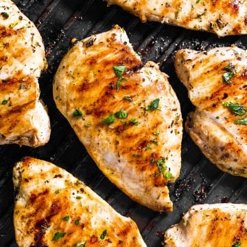 overhead view of several chicken breasts on table grill