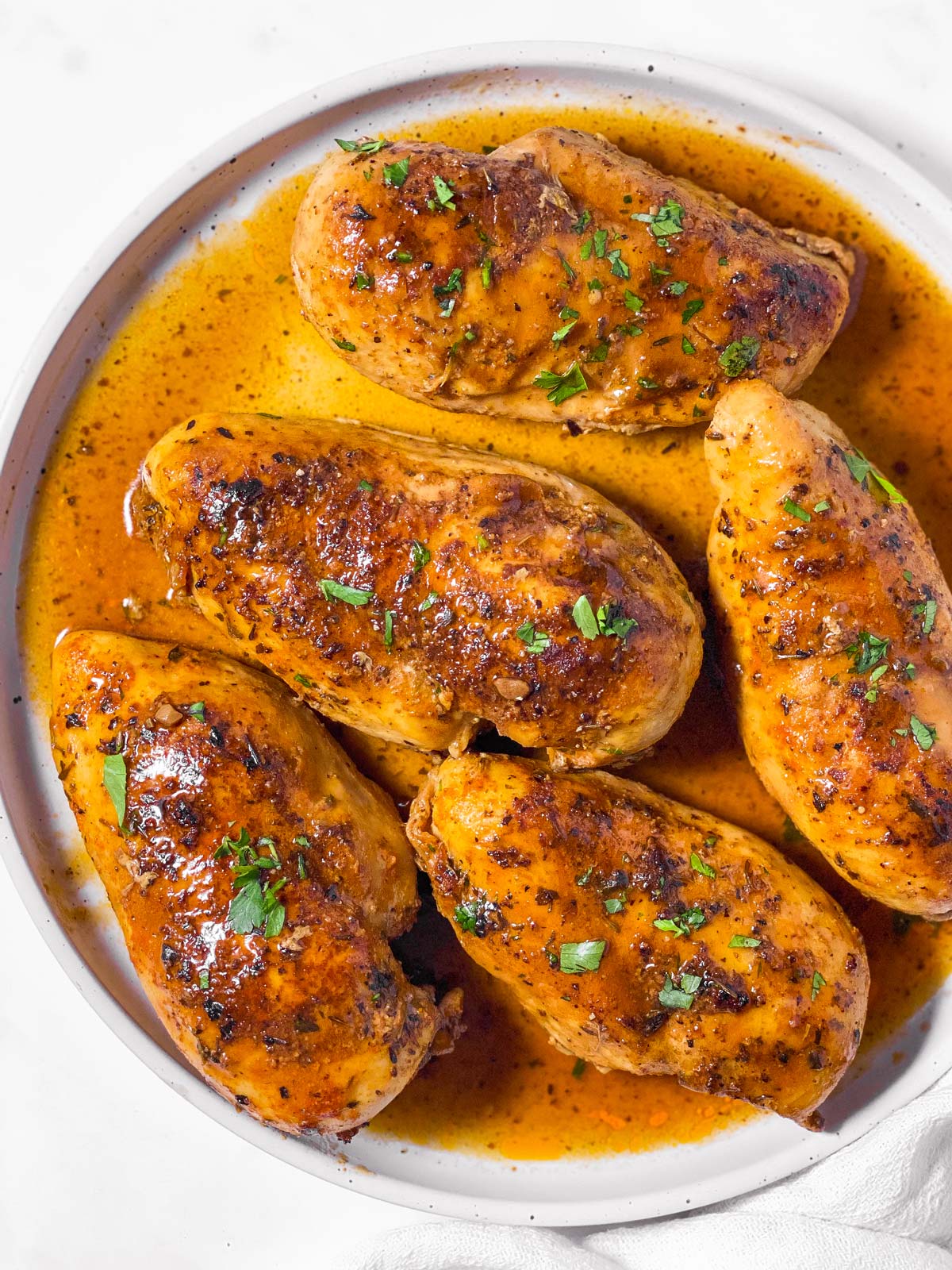 overhead view of instant pot chicken breast in sauce on white plate