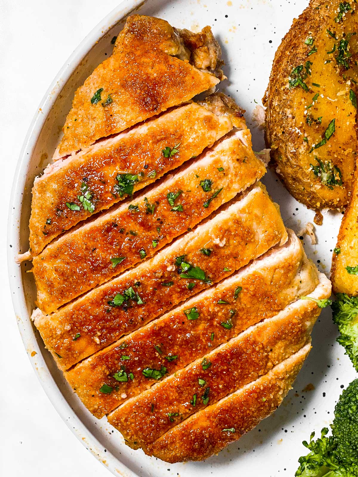 overhead view of sliced boneless pork chop on white plate