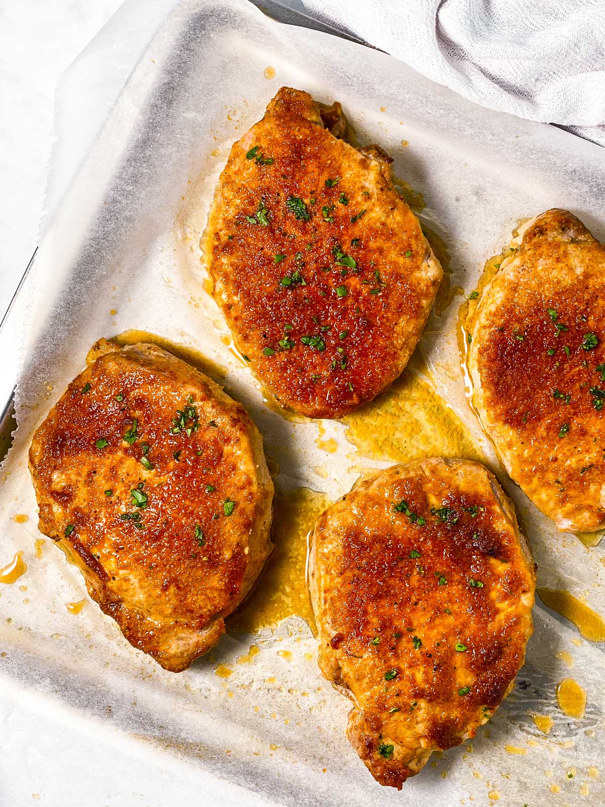 four oven baked boneless pork chops on a lined baking sheet