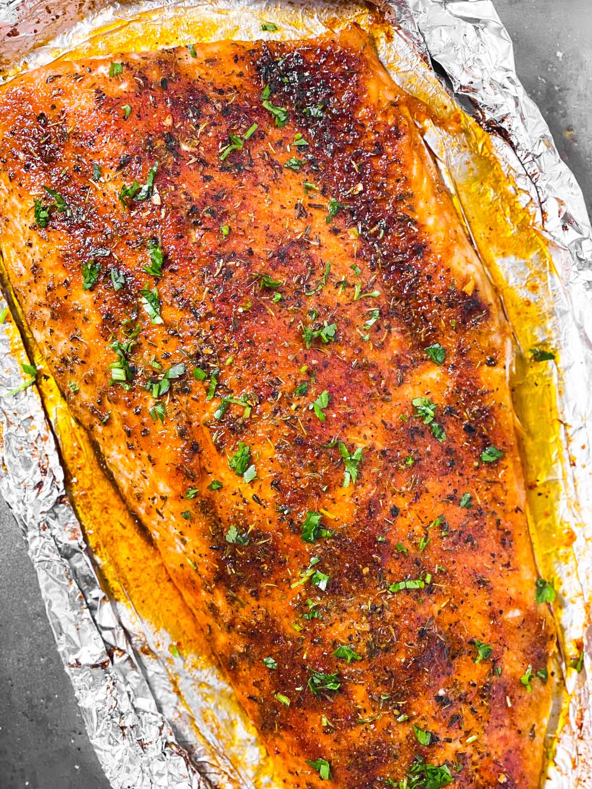 overhead close up view of oven baked salmon fillet sprinkled with chopped parsley