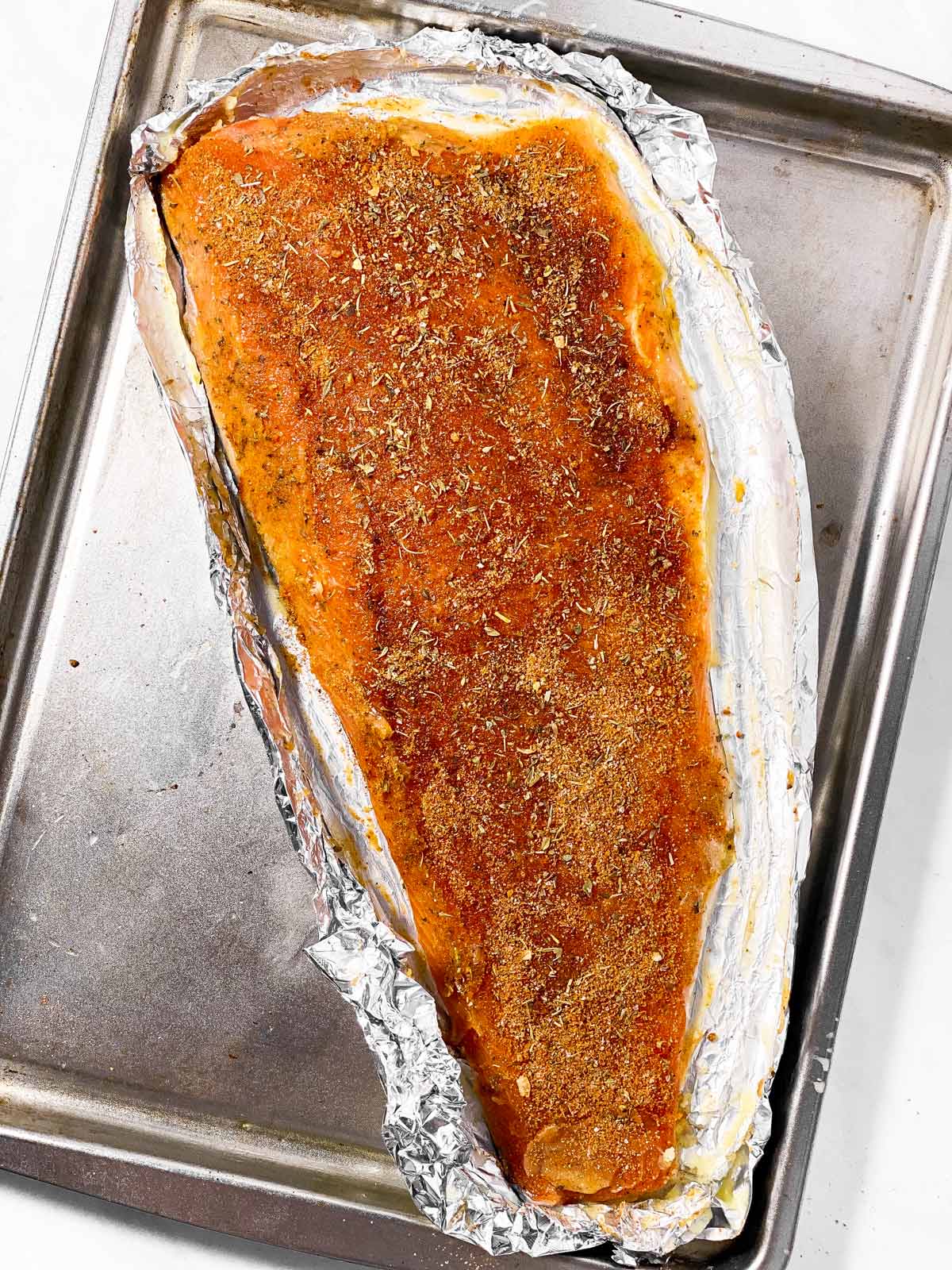 seasoned salmon fillet on baking sheet