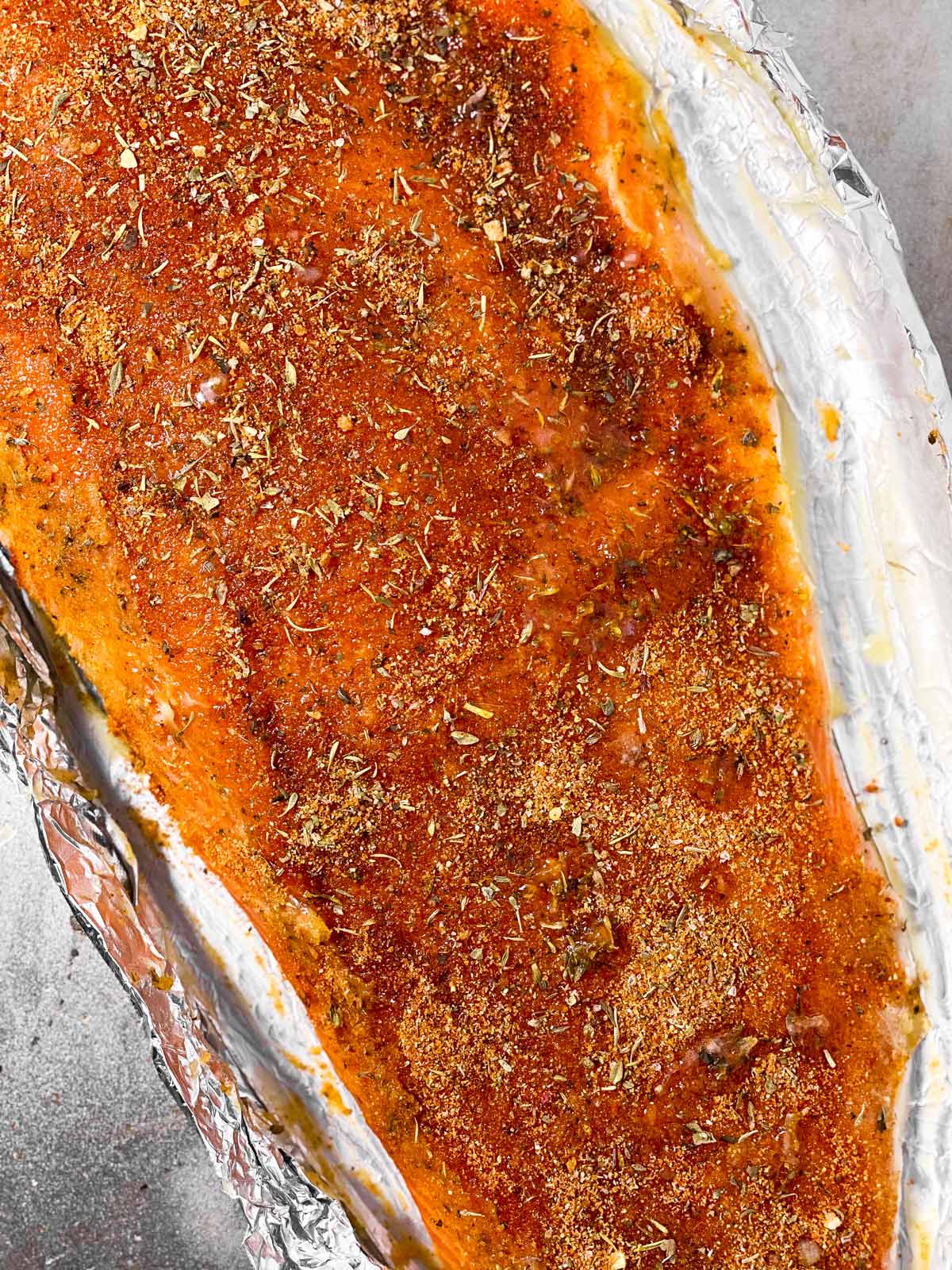 seasoned raw salmon fillet on foil lined baking sheet