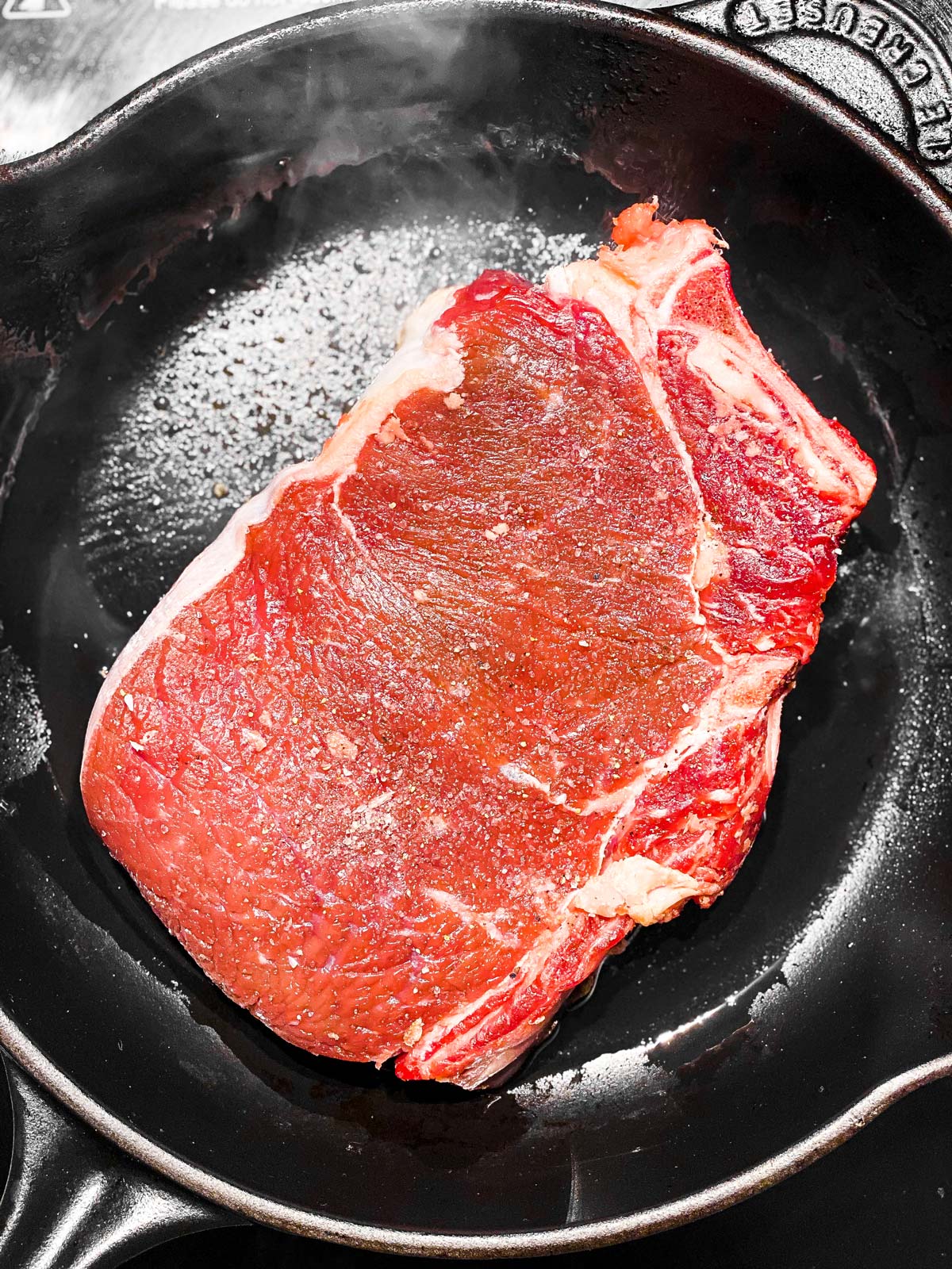 steak in smoking cast iron skillet