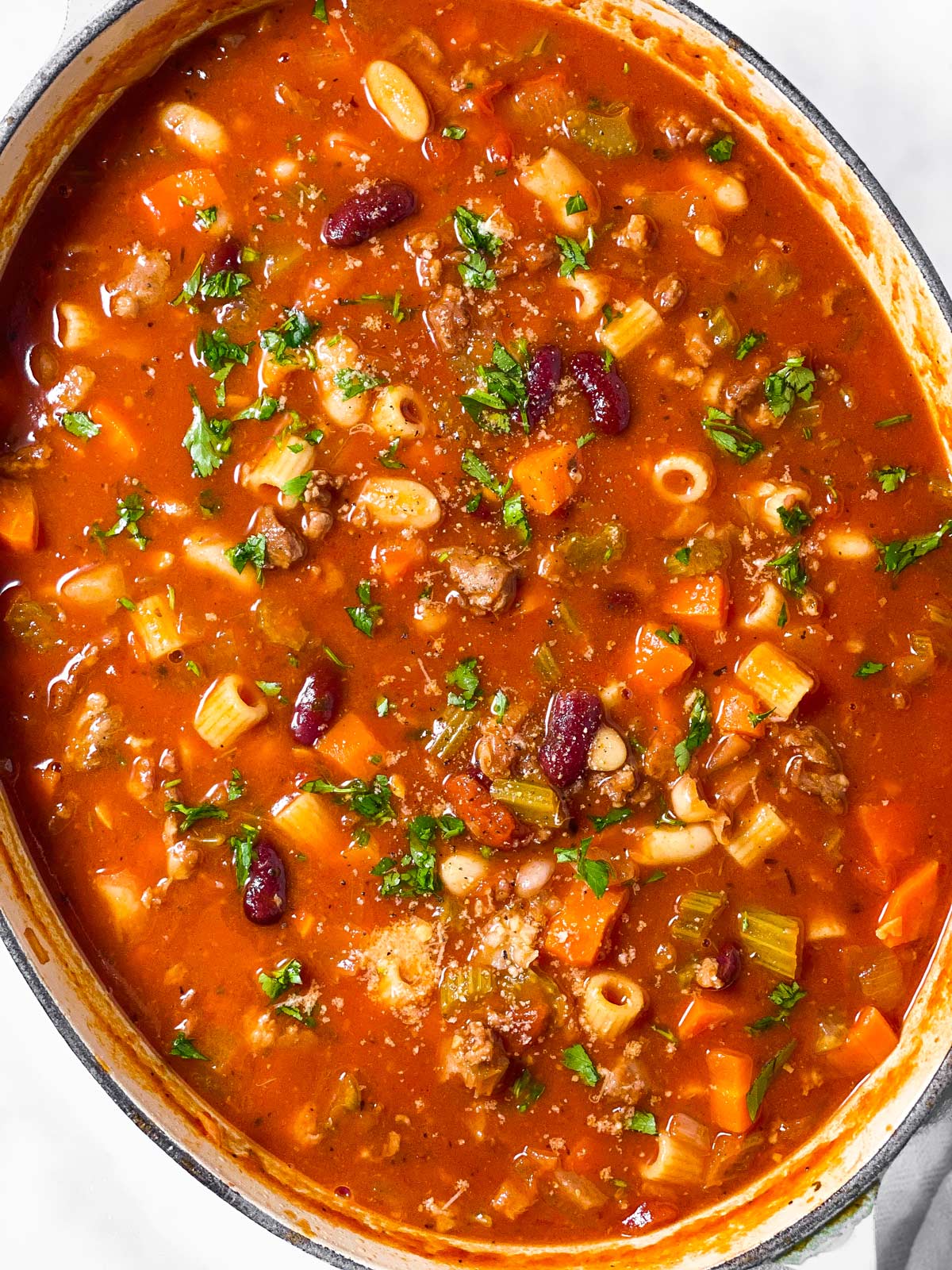 pasta fagioli soup in oval Dutch oven garnished with chopped parsley