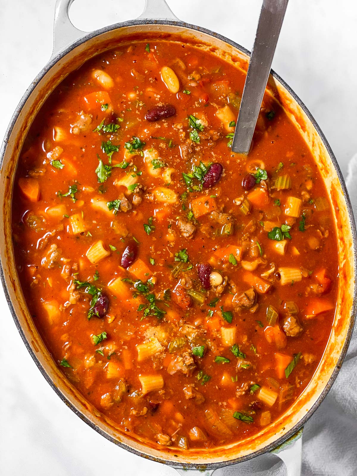 overhead view of oval white pot filled with pasta fagioli soup