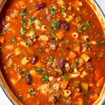 overhead view of oval white pot filled with pasta fagioli soup